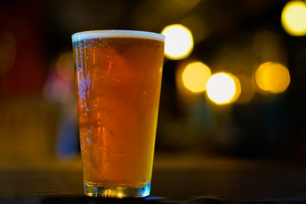 Copo de cerveja sem marca em um bar à noite, representando o tema álcool e ereção